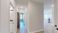 Located at 801 Shell Dr in Spring Lake, NC, this well-designed single-story home offers three bedrooms, two bathrooms, and a thoughtfully organized layout. Light wood-tone flooring flows consistently throughout, creating a bright and cohesive aesthetic across all rooms.

The combined kitchen and living area serves as the heart of the home. The kitchen is outfitted with white shaker cabinetry, granite countertops, a classic subway tile backsplash, and stainless steel appliances, including a French door refrigerator. A glass-panel back door and adjacent window in the dining area flood the space with natural light and provide outdoor access.

The spacious primary bedroom features a ceiling fan and connects directly to a private en suite bathroom. The bathroom is appointed with granite-topped vanity cabinetry, a large framed mirror, and direct access to a generous walk-in closet equipped with wire shelving. Two additional bedrooms are well-proportioned — one with corner windows offering abundant natural light, and another with its own closet featuring built-in wire shelving.

A central hallway connects all rooms efficiently, complemented by recessed lighting and clean white trim throughout. The home also includes a dedicated laundry room and three closets in total, providing ample storage. The neutral color palette and modern finishes give the home a fresh, move-in-ready appeal.