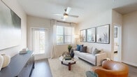 Located in Katy, TX, this 2-bedroom, 2-bathroom single-floor residence offers a thoughtfully designed layout with modern finishes throughout. The open-concept kitchen and living area serves as the heart of the home, anchored by a granite-topped island with built-in shelving and seating for two. White shaker cabinetry, a subway tile backsplash, stainless steel appliances, and wood-look flooring complete the kitchen's clean, contemporary aesthetic. The adjoining living room is bright and inviting, featuring a ceiling fan, large windows with sheer drapes that welcome natural light, and direct access to an outdoor area. Both bedrooms are carpeted and well-sized, with the primary bedroom offering ample room for a queen or king bed. Each bedroom is served by its own bathroom, both finished with granite-topped dual vanities, white cabinetry with brushed nickel hardware, and wood-look flooring. Two generously sized walk-in closets provide abundant storage, each equipped with multi-tiered hanging rods and shelving. The overall ambiance of the space is bright, neutral, and modern, creating a comfortable and functional living environment.