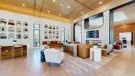 Located at 25440 Solaris Pl in Murrieta, CA, this single-floor amenity space offers a thoughtfully designed environment for gathering, recreation, and relaxation. The interior showcases a cohesive modern aesthetic defined by soaring vaulted ceilings with warm wood paneling, large black-framed windows, and expansive porcelain tile flooring throughout.

The main lounge is a standout centerpiece, featuring a dramatic built-in fireplace framed by a bold dark archway, a wall-mounted television, and plush seating arrangements that invite socializing. Warm terracotta-toned sofas and accent chairs complement a textured wood-clad feature wall, adding depth and warmth to the space. A full-size pool table anchors the recreational zone, while direct access to the outdoor patio brings in ample California sunshine.

The dining room is bright and airy, with a long solid-wood communal table surrounded by upholstered chairs, soaring ceilings with curved wood detailing, and panoramic windows framing outdoor views. Adjacent to it, a casual bar area offers high-top seating and seamless access to an outdoor patio with shaded seating.

A dedicated golf simulator room rounds out the amenities, complete with a turf hitting surface, projection screen, acoustic wall panels, and a full AV control station. Arched display niches along the lounge walls add an artful architectural touch throughout.