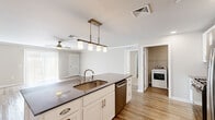 Located at 1130 Alexandra Ln in Harrisburg, PA, this well-appointed 2-bedroom, 2-bathroom single-floor home offers a comfortable and functional layout. The modern kitchen is a standout feature, showcasing white shaker cabinetry, dark granite countertops, a mosaic tile backsplash, stainless steel appliances including a gas range, microwave, and French door refrigerator, and a large island with pendant lighting and a undermount sink — all set over durable wood-look flooring. The living room is bright and airy, featuring sliding glass doors with vertical blinds that invite natural light and provide outdoor access. Crown molding adds a refined touch to the space. Both bedrooms are generously sized and finished with plush carpeting and ceiling fans. The spacious primary bedroom connects to a private bathroom and includes a large walk-in closet with wire shelving. The second bedroom also features a ceiling fan and a well-sized window. Both bathrooms are clean and functional, featuring white vanity cabinetry and wood-look flooring. A dedicated laundry room with a full-size GE washer and dryer adds everyday convenience. The home's neutral tones and consistent finishes throughout create a cohesive and move-in-ready living environment.