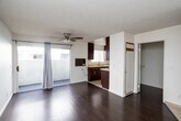 Located in the Koreatown neighborhood of Los Angeles, this single-floor unit at 864 S New Hampshire Ave offers a clean, functional layout with thoughtful finishes throughout. The living area is spacious and bright, featuring rich dark hardwood flooring, crisp white walls, and a textured ceiling with a ceiling fan. Sliding glass doors open to a private balcony, allowing natural light to fill the room and providing a seamless connection to the outdoors. An additional room with matching hardwood floors and a textured ceiling offers versatile space suitable for a bedroom or office. The kitchen is efficiently designed with rich dark wood cabinetry accented by sleek bar-pull hardware, light-toned countertops, a double-basin stainless steel sink, tile flooring, and includes a dishwasher and range. The bathroom is well-appointed with a dark wood vanity, a warm-toned countertop with an undermount sink, a large mirror, and a full shower-tub combination with sliding doors. The overall ambiance of the unit is clean and neutral, offering a comfortable and move-in-ready living environment in a highly accessible Los Angeles location.