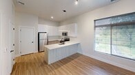 This 510 square foot apartment offers a thoughtful design that maximizes space and functionality. The single-floor layout comprises one bedroom, one bathroom, and an open-concept living area. The primary bedroom, measuring 140 square feet, provides ample space for rest and relaxation.

The apartment features a modern aesthetic with clean lines and a neutral color palette. Large windows with horizontal blinds allow natural light to flood the space, creating an airy and open atmosphere. The floors are a combination of warm wood-look vinyl in the main living areas and plush carpeting in the bedroom, adding comfort and visual interest.

The kitchen is a highlight, boasting sleek white cabinetry, stainless steel appliances, and a practical island that doubles as a dining area. The streamlined design includes ample counter space and storage, making it both functional and visually appealing.

The bathroom continues the modern theme with a clean, minimalist design. It features wood-look flooring, a vanity with storage, and essential fixtures that complement the overall style of the apartment.

Throughout the space, recessed lighting and strategically placed fixtures provide warm, even illumination. The open floor plan allows for flexible furniture arrangements, making it easy to personalize the space to individual needs and preferences.

Despite its compact size, this apartment offers an efficient and stylish living solution, ideal for those seeking a low-maintenance yet comfortable urban dwelling.