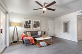 This single-floor residence offers a thoughtfully designed layout that balances comfort and functionality throughout. The living area features rich dark hardwood-style flooring, a ceiling fan, and a sliding glass door that opens directly onto a private patio, flooding the space with natural light and providing seamless indoor-outdoor connectivity. A vertical green wall accent adds a distinctive touch to the living space.

Adjacent to the living area, the dining space benefits from a generous arrangement of windows on multiple walls, creating a bright, airy atmosphere ideal for everyday meals or entertaining. The galley-style kitchen is outfitted with white cabinetry, subway tile backsplash, dark countertops, and stainless steel appliances, offering an efficient and clean workspace.

The residence includes two well-proportioned bedrooms, each with plush carpeting, ceiling fans, and ample natural light from large windows. The bedrooms provide a calm, restful retreat.

The bathroom is finished with white shaker-style cabinetry, a wide vanity with an extended countertop, a large mirror, and tile flooring, offering both practicality and a clean aesthetic. The private patio extends the living space outdoors, providing a dedicated area for relaxation surrounded by lush greenery.