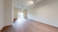 Located at 1235 NASA Pkwy in Houston, TX, this thoughtfully designed 2-bedroom, 2-bathroom residence offers a comfortable and modern living experience across a single floor. The open-concept living and kitchen area is anchored by warm hardwood-style flooring, recessed lighting, and a ceiling fan, creating a bright and inviting atmosphere. The kitchen is a standout feature, boasting rich dark wood cabinetry, granite countertops, a subway tile backsplash with under-cabinet lighting, stainless steel appliances including a gas range, microwave, refrigerator, and dishwasher, plus a central island for additional prep space. Both bedrooms are carpeted and equipped with ceiling fans; the primary bedroom opens to a private balcony with decorative ironwork railing. The primary bathroom impresses with large-format marble-look tile flooring, a dual-sink granite vanity, and a glass-enclosed walk-in shower. The secondary bathroom mirrors the same refined tile work and granite countertop details. A spacious walk-in closet with wire shelving provides ample storage. Clean white walls and neutral tones throughout lend the space a polished, move-in-ready feel.