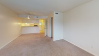 This two-floor residential space offers a practical and comfortable layout designed for everyday living. The open living area is finished with plush wall-to-wall carpeting and features a ceiling fan with integrated lighting, providing both comfort and airflow. A textured ceiling adds subtle character throughout the common areas. The living space flows seamlessly toward the kitchen, which is visible through a pass-through counter. The kitchen is efficiently laid out with ample white cabinetry, wood-toned laminate countertops, a double sink, a dishwasher, a full-size refrigerator, and a coil-burner electric range — all finished in white for a clean, cohesive look. Vinyl tile flooring completes the kitchen's functional design. The bedrooms are generously proportioned, each featuring soft carpeted floors, ceiling fans with light kits, and windows fitted with horizontal blinds that allow natural light to filter in while maintaining privacy. The bathroom includes a full-size soaking tub with a tiled surround and built-in shelving for added convenience. Throughout the space, a neutral color palette of whites and warm beiges creates a bright, clean atmosphere that is easy to personalize.