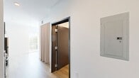 Located at 120 20th Ave S in Nashville, TN, this efficiently designed studio presents a clean, contemporary aesthetic throughout its single floor. The combined kitchen and living area forms the heart of the space, featuring warm-toned hardwood-style flooring that runs seamlessly throughout. The kitchen is outfitted with modern gray cabinetry, granite countertops, stainless steel appliances including a range, dishwasher, refrigerator, and microwave, along with a stainless steel sink — providing a fully functional culinary setup. A bold dark-framed door adds a striking contrast against the crisp white walls, reinforcing the modern design language. Floor-to-ceiling windows fitted with horizontal blinds flood the living area with abundant natural light and frame views of the surrounding Nashville cityscape, creating an open, airy feel. Neutral-toned floor-length curtains add a soft, elegant touch to the living space. The bathroom continues the minimalist aesthetic with light flooring and clean white walls. A dedicated closet provides practical storage. The overall ambiance is bright, modern, and thoughtfully organized, making efficient use of every square foot in this well-appointed Nashville studio.