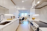 Located in the desirable Kalorama neighborhood of Washington, DC, this thoughtfully designed two-bedroom, one-bathroom residence offers a clean, modern aesthetic across a single floor. The galley-style kitchen is a standout feature, lined with floor-to-ceiling white cabinetry, under-cabinet lighting, quartz countertops, a marble-style backsplash, and stainless steel appliances including a professional-grade range with overhead ventilation hood. Light wood flooring runs throughout, enhancing the bright, airy atmosphere. The open-plan layout flows seamlessly from the kitchen into the dining area and living room, where dual windows flood the space with natural light and offer views of the surrounding Washington streetscape. The living room features recessed lighting and a clean white palette. Both bedrooms are well-proportioned, each with large windows that invite natural light and views of the cityscape; one bedroom includes a large sliding-door closet. The bathroom is finished with warm wood-toned wall tiles, a glass-enclosed walk-in shower with a rainfall showerhead, and a modern vanity. Three closets provide ample storage throughout the unit. The entrance and hallway connect all areas efficiently, completing this well-appointed urban residence.