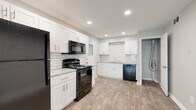 This single-floor unit offers a thoughtfully updated interior with a clean, modern aesthetic throughout. The kitchen serves as a functional centerpiece, showcasing white shaker-style cabinetry paired with granite-look countertops, a classic white subway tile backsplash, and a full suite of black appliances including a range, microwave, dishwasher, and refrigerator. Wood-look plank flooring runs through the kitchen and flows into the open living area, which is bright and airy with recessed lighting and neutral grey-toned walls that create a calm, welcoming atmosphere. A front-facing window allows natural light to fill the living space. Multiple bedrooms feature plush wall-to-wall carpeting and individual windows fitted with blinds, providing comfort and privacy with views of surrounding greenery. The bathrooms are finished with wood-look tile flooring, sleek white vanities, and accessible grab bars, combining practicality with a clean, contemporary look. The unit's consistent use of neutral tones, updated finishes, and durable flooring materials gives the entire space a cohesive and move-in-ready appeal.
