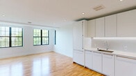 Located at 1650 Harvard St NW in Washington, DC's sought-after Columbia Heights neighborhood, this thoughtfully designed 3-bedroom, 1-bathroom unit offers a clean, modern aesthetic throughout its single floor. Warm hardwood flooring flows continuously across all rooms, creating a cohesive and inviting atmosphere. The open-concept living and kitchen area is anchored by a contemporary all-white kitchen featuring flat-front cabinetry, integrated appliances, and recessed lighting, seamlessly connecting to the living space. Bold black-framed grid windows flood the area with natural light and frame views of the surrounding neighborhood's lush tree canopy. The primary bedroom is a well-proportioned retreat featuring multiple large windows that bring in abundant daylight and urban views. All three bedrooms are finished with the same hardwood floors and crisp white walls, and each includes sliding closet doors for efficient storage. The bathroom is finished with neutral tile flooring, a window offering natural light and neighborhood views, and clean modern fixtures. A connecting hallway links the bedrooms efficiently, and recessed lighting throughout the unit adds a polished, contemporary feel. The overall ambiance is bright, clean, and move-in ready.