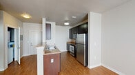 This single-story, one-bedroom, one-bathroom unit offers a practical and well-designed layout making efficient use of its space. The kitchen serves as a central feature, showcasing dark espresso cabinetry with ample storage, granite-style countertops, and a full suite of stainless steel appliances including a refrigerator, range, and microwave. A peninsula with a double basin sink and additional counter space extends into the living area, creating a natural partition between the kitchen and the open living space. Hardwood-style flooring runs throughout the main living and kitchen areas, adding warmth and visual continuity.

The bedroom is a comfortable, carpeted room featuring a ceiling fan with light fixture and a window with blinds that brings in natural light. It connects seamlessly to the rest of the unit via a clean, neutral-toned hallway. The bathroom includes a granite-style vanity with an undermount sink, a large mirror, tile flooring, and a full soaking tub with shower combination. Ceiling fans in both the living and bedroom areas enhance comfort. The overall aesthetic is clean and neutral, with white walls and consistent finishes throughout.