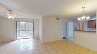 This single-floor residence offers a well-organized layout with a variety of functional spaces throughout. The living area is bright and open, featuring polished tile flooring and a ceiling fan, with a warm accent wall adding character. A large sliding glass door with vertical blinds fills the space with natural light and provides access to an outdoor area, offering views of surrounding greenery.

Adjacent to the living area, the dining space benefits from additional natural light through a wide window framed by lush outdoor vegetation. The kitchen is efficiently designed with warm oak cabinetry, granite-style countertops, and a full suite of black appliances including a range, microwave, and refrigerator, all set atop light tile flooring.

The bedrooms feature rich wood-look laminate flooring, textured ceilings, and windows fitted with blinds that allow for ample natural light. Each room offers a clean, neutral palette that provides versatile styling options.

The bathrooms are finished with granite countertops and rich wood cabinetry. The full bathroom includes a double-sink vanity with a large mirror, a bathtub/shower combination, and tile flooring. A second bathroom provides a single-sink vanity with similar finishes. Together, the spaces create a cohesive, comfortable living environment.