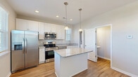 Located at 2314 Doveshell Dr in North Myrtle Beach, SC, this two-story, 3-bedroom, 3-bathroom home offers a well-designed layout spread evenly across two floors. The main level features an open-concept kitchen, dining, and living area. The kitchen is a standout, showcasing white shaker-style cabinetry, granite countertops, a central island with pendant lighting, and a full suite of stainless steel appliances including a range, microwave, and refrigerator — all set atop warm hardwood-style flooring. Natural light pours in through multiple windows fitted with blinds. A patio extends the living space outdoors, ideal for relaxing in the coastal South Carolina climate. Also on the main level is a laundry area and a full bathroom. Upstairs, three bedrooms provide comfortable accommodations. The spacious primary bedroom features a tray ceiling with ceiling fan, plush carpeting, and a walk-in closet with built-in wire shelving. Its en-suite bathroom includes a double granite vanity and a glass-enclosed shower. Additional bedrooms offer hardwood-style flooring, ceiling fans, and ample natural light. A second full bathroom with a tub-shower combo and granite vanity serves the remaining bedrooms. Four closets throughout ensure generous storage across the home.
