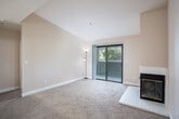Located at 5639 Jacquiline Way in Livermore, CA, this two-bedroom, three-bathroom single-floor residence offers a well-organized layout with a comfortable blend of functionality and character. The open-concept living and dining area is anchored by a white-tiled fireplace with a classic gold-trimmed glass surround, rising toward vaulted ceilings that lend a sense of spaciousness to the room. Plush carpeting runs throughout the living spaces and bedrooms, while the kitchen and bathrooms feature light hardwood-style flooring. Sliding glass doors in the living room lead directly to a private balcony with views of surrounding greenery, filling the space with natural light. The kitchen is efficiently designed in a galley configuration, featuring white cabinetry, a skylight, a ceiling fan, and white appliances including an electric range and refrigerator. The primary bedroom is generously sized with a large window overlooking outdoor greenery and ample closet space. The bathrooms are clean and functional, with one featuring a wide vanity with updated white cabinetry and a glass-enclosed tub-shower combo. A dedicated laundry area and utility room add everyday convenience, completing this practical and comfortable Livermore residence.