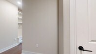 This single-story, 2-bedroom, 2-bathroom home offers a thoughtfully designed layout that maximizes functionality and comfort. The living room serves as the heart of the home, featuring warm wood-style flooring, a ceiling fan, and generous natural light streaming through multiple windows with blinds and a set of French doors that open to the outdoors. The kitchen is a standout feature, showcasing crisp white shaker cabinets, quartz countertops, a central island with a matte black sink faucet, stainless steel appliances, and recessed lighting—combining style with practicality. Both bedrooms are carpeted and equipped with ceiling fans; the primary bedroom offers a comfortable footprint, while the second bedroom benefits from dual windows that bring in ample natural light. Two well-appointed closets provide organized storage with built-in shelving and hanging rods. The bathrooms are finished with white shaker vanity cabinetry, quartz countertops, large framed mirrors, matte black hardware, and wood-style flooring. Throughout the home, neutral beige tones on the walls and white trim create a clean, cohesive aesthetic. Multiple hallways connect the spaces efficiently, contributing to a smooth and functional floor plan.