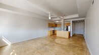 This single-floor residence in downtown Baton Rouge offers a thoughtfully designed layout with a clean, modern aesthetic throughout. The open-concept living area is anchored by polished concrete floors that reflect natural light, with an exposed structural column adding an industrial character to the space. A ceiling fan overhead enhances comfort in the generously sized main living area, which benefits from large windows framing views of the surrounding cityscape.

The kitchen is well-appointed with light wood cabinetry, marble-look countertops and backsplash, stainless steel appliances including a range and refrigerator, and a peninsula that provides additional prep and seating space. The layout promotes seamless flow between the kitchen and living areas.

A hallway lined with sliding glass-panel doors leads to the two bedrooms, each featuring plush carpeting, ceiling fans, and reach-in closets with built-in rods. The bedrooms are bright, with one offering direct views of the city skyline through large windows.

Both bathrooms are finished in a crisp, minimal style with white tile, mosaic tile flooring, warm wood vanities, and marble-top sinks. One bathroom includes a soaking tub and tiled shower, while the other features a glass-enclosed shower stall, offering distinct functionality for each.