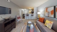 Located at 9258 Hanover Crossing Dr in Mechanicsville, Virginia, this single-floor residence offers a thoughtfully designed layout that balances comfort and functionality. The open-concept living area features plush carpeting, neutral gray walls, and large windows that invite natural light, creating a bright and welcoming atmosphere. A wall-mounted television and ample seating make the living room an ideal space for relaxation. The kitchen is a standout feature, boasting rich dark cabinetry, light granite-style countertops, black appliances including a range and built-in microwave, and hardwood-style flooring. A breakfast bar with pendant lighting connects the kitchen to a casual dining area, enhancing the open feel. The bedrooms are generously proportioned, each carpeted and painted in soft, calming tones with large windows dressed in stylish curtains. The primary bedroom offers ample space for a full furniture suite. The bathrooms are clean and well-finished, featuring dark wood vanities with white countertops, tile-style flooring, and a tub-shower combination. Throughout the residence, a cohesive neutral color palette with warm accent tones ties each space together for a polished, move-in-ready aesthetic.