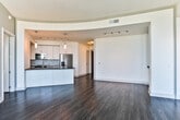 Located in the heart of Midtown Atlanta at 890 Juniper St NE, this contemporary high-rise unit offers a sophisticated urban living experience defined by sleek finishes and stunning panoramic views of the Atlanta skyline. Dark hardwood flooring flows consistently throughout the living spaces, complementing the clean, neutral color palette of the walls and ceilings.

The open-concept living and dining area is anchored by dramatic floor-to-ceiling corner windows that flood the space with natural light and frame sweeping city views. A curved ceiling detail adds architectural interest to the transition between the living area and kitchen.

The kitchen features white shaker cabinetry, dark countertops, a decorative tile backsplash, and a full suite of stainless steel appliances, including a French door refrigerator, range, microwave, and dishwasher. A breakfast bar provides casual seating and separates the kitchen from the main living area.

The bedrooms are well-appointed, each with dark hardwood floors and generous closet space. One bedroom includes a walk-in closet with built-in shelving and hanging rods. The primary bathroom offers a double-sink vanity with dark countertops, a soaking tub, a separate glass-enclosed shower with marble-style tile surround, and large-format floor tile. A secondary bathroom includes a tub-shower combo with matching marble-style tile.