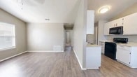 Located at 1625 Sunset Dr in San Angelo, TX, this single-story, 2-bedroom, 1-bathroom home offers a well-organized layout with a clean, neutral aesthetic throughout. The open-concept living area features durable wood-look flooring, vaulted ceilings that enhance the sense of space, and multiple windows with blinds that allow natural light to fill the room. A coat closet is conveniently positioned near the front entry. The kitchen runs along a galley-style configuration, outfitted with white cabinetry, light countertops, and black appliances including a range, microwave, and refrigerator. A peninsula counter connects the kitchen to the living area, creating a natural flow between the two spaces. Both bedrooms are carpeted and include ceiling fans and windows with blinds. The primary bedroom features vaulted ceilings and hardwood-look flooring, adding a standout touch, while the second bedroom offers a cozy, carpeted retreat. A dedicated walk-in closet with built-in shelving and hanging rods provides ample storage. The bathroom is equipped with a full soaking tub and shower combo with a white surround. Warm taupe walls and consistent finishes throughout give the home a cohesive, move-in-ready appeal.