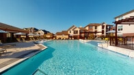 Located at 5330 Sienna Pkwy in Missouri City, TX, this outdoor amenity space is part of a thoughtfully designed residential community that blends modern aesthetics with comfortable communal living. The centerpiece of the space is a generously sized resort-style swimming pool with crystal-clear water, surrounded by a spacious sundeck outfitted with lounge chairs and patio umbrellas, ideal for relaxation under the Texas sun.

Adjacent to the pool, a beautifully paved lounge area features stylish outdoor seating with contemporary furniture, including cushioned chairs and accent tables, set against a backdrop of lush landscaping and manicured greenery. The cobblestone paver surfaces extend throughout the outdoor areas, lending a refined and cohesive look to the grounds.

The community's brick exterior architecture is both classic and durable, with warm red brick facades accented by stone detailing. A covered patio corridor connects interior amenity spaces to the outdoors through large sliding glass doors, creating a seamless indoor-outdoor flow. This shaded walkway is furnished with additional seating, making it a welcoming transition space. An additional covered outdoor lounge features an outdoor television, perfect for gathering, and offers open views of the community's courtyard and pool area. The overall ambiance is vibrant, inviting, and well-suited for both relaxation and social engagement.