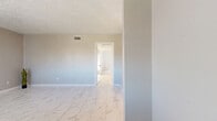 This single-story, 2-bedroom, 1-bathroom residence offers a thoughtfully arranged layout that maximizes its compact footprint. Marble-look porcelain tile flooring flows throughout the main living areas, including the living room, dining room, hallway, and kitchen, lending a clean and cohesive aesthetic across the space.

The living and dining areas are bright and open, benefiting from natural light filtering through vertical blinds. A textured ceiling adds dimension overhead, while neutral-toned walls provide a versatile backdrop throughout. The galley-style kitchen is efficiently designed with gray cabinetry, granite countertops, a marble-look tile backsplash, and black appliances, making the most of the available space.

Both bedrooms feature plush wall-to-wall carpeting and are served by three closets total, offering ample storage. The primary bedroom includes a ceiling fan with lighting and a sliding door framed by vertical blinds. The secondary bedroom also benefits from natural light and convenient access to shared spaces.

The bathroom is well-appointed with a granite-topped vanity, marble-look tile flooring, and a tiled tub-shower combination. A connecting hallway ties all rooms together, contributing to the home's efficient and functional flow throughout.