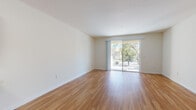 This well-appointed single-floor residence offers a clean, modern aesthetic throughout its thoughtfully designed layout. The open living area is highlighted by warm hardwood-style flooring that extends seamlessly across the space, while large sliding glass doors lead to a private balcony, inviting abundant natural light and providing pleasant views of surrounding greenery. The bright, neutral-toned walls enhance the airy feel of the living space.

The kitchen is a standout feature, outfitted with rich, dark espresso cabinetry contrasted by light countertops. A full suite of stainless steel appliances — including a refrigerator, electric range, microwave, and dishwasher — completes the functional and stylish cooking space. The kitchen opens toward the main living area, creating an accessible and connected layout.

The bedrooms are finished with soft, neutral carpeting and feature windows that bring in natural light and outdoor views, contributing to a calm and comfortable atmosphere. Additional rooms offer versatile space with the same consistent neutral palette.

The bathroom is clean and practical, featuring a dark-toned vanity with a single sink, a large mirror, and a tub-shower combination. Hardwood-style flooring carries into this space as well, tying the overall design together cohesively.