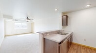 Located at 1211 Enterprise Dr E in Belle Plaine, MN, this one-bedroom, one-bathroom unit offers a well-designed single-floor layout that maximizes functionality and comfort. The open-concept kitchen and living area form the heart of the unit, with the kitchen featuring rich dark-toned cabinetry, granite-style laminate countertops with a breakfast bar peninsula, a double-basin sink, and a full suite of stainless steel appliances including a refrigerator, range, microwave, and dishwasher. Light wood-look flooring runs throughout the kitchen, providing a warm contrast to the neutral walls. The adjoining living room is carpeted and benefits from natural light, with a ceiling fan adding comfort and airflow. The spacious bedroom features plush carpeting, a ceiling fan, and a generous closet, along with dual windows that bring in abundant natural light and outdoor views. The full bathroom is clean and modern, appointed with dark wood cabinetry, a white countertop vanity, a framed mirror, and a full tub-shower combination with white surround. A dedicated laundry area adds everyday convenience to this efficiently organized unit.