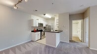 Located at 2450 Lake Debra Dr in Orlando, FL, this one-bedroom, one-bathroom unit is thoughtfully laid out across a single floor, offering an efficient and functional use of space. The open-concept kitchen and living area form the heart of the home, where the kitchen features white cabinetry, dark countertops, tile flooring, and a full suite of stainless steel appliances including a range, microwave, and refrigerator. A peninsula-style breakfast bar separates the kitchen from the carpeted living area, which includes built-in shelving, a ceiling fan, and access to the front entry. Natural light filters in alongside a sliding door opening to the exterior. A hallway connects the main living area to the private bedroom, which offers plush carpeting, a ceiling fan, and a generous closet for storage. The full bathroom is finished with wood-style flooring, a vanity with dark countertop, and a tub-shower combination with white tile surround. A dedicated laundry room accommodates a full-size washer and dryer and includes wire shelving and a water heater. The overall aesthetic is clean and neutral throughout, with warm beige tones and white trim creating a bright, move-in ready environment.