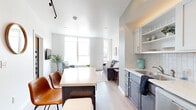 This thoughtfully designed 2-bedroom, 1-bathroom unit in Waterloo, Iowa offers a clean, modern aesthetic throughout its efficiently utilized single-floor layout. The open-concept living and kitchen area serves as the heart of the space, where light hardwood-style flooring, crisp white walls, and recessed and track lighting create a bright, contemporary ambiance.

The kitchen is well-appointed with stainless steel appliances including a refrigerator, range, microwave, and dishwasher. Two-tone cabinetry — white upper cabinets with a subway tile backsplash and darker lower cabinets — pairs with light quartz countertops for a stylish, functional workspace. A central island with seating provides additional prep space and casual dining.

The living room features oversized windows that flood the area with natural light and offer views of the Waterloo cityscape, enhancing the open feel of the space. Both bedrooms are comfortably scaled, with the primary bedroom accessed through a sliding barn door and featuring soft carpet flooring and tray ceiling details. The bathroom includes a combined tub and shower, a single vanity with coordinating cabinetry, and tile flooring. The overall design is cohesive, modern, and move-in ready.