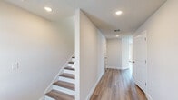 This two-story home offers a practical and comfortable layout across two floors. The main level features a living room, a fully equipped kitchen, and an attached garage. The kitchen stands out with its crisp white shaker cabinetry, granite countertops, subway tile backsplash, a central island, and stainless steel appliances — all complemented by light wood-look flooring that flows throughout the main living areas. A staircase with wood-toned treads and clean white risers connects the floors, flanked by a bright hallway with recessed lighting and a textured ceiling.

Upstairs, the primary bedroom is a spacious retreat featuring vaulted ceilings, a ceiling fan, and direct access to an en-suite bathroom and a walk-in closet. Three additional bedrooms offer wood-look or carpeted flooring and natural light through window blinds. Multiple closets — including wire-shelved walk-ins — provide ample storage throughout. A dedicated laundry room includes washer/dryer hookups, shelving, and an ice maker connection. The four bathrooms are clean and functional, with neutral finishes. The attached garage features an automatic opener and a concrete floor, completing this well-appointed home.