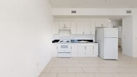 Located at 405 E 7th St in Hialeah, FL, this one-bedroom, one-bathroom unit offers a clean, bright, and efficiently designed living space spread across a single floor. The interior is unified by light-toned ceramic tile flooring and crisp white walls, creating a fresh and airy atmosphere throughout.

The open-plan living and kitchen area provides a functional layout with ample room for daily living. The kitchen is well-equipped with white cabinetry offering generous storage, dark granite-style countertops, a white electric range, under-cabinet ventilation hood, a double sink, and a full-size refrigerator — all set against a bright white backdrop.

The bedroom is a comfortable, well-proportioned room featuring a large window with slatted blinds that allows natural light to filter in while maintaining privacy. A walk-in closet with built-in shelving provides excellent storage capacity, and a second closet adds further organizational flexibility.

The bathroom is neatly appointed with white tile walls surrounding a full bathtub and shower combination, a toilet, and a vanity with dark countertop and mirror. A small window brings in natural light. The unit also includes a dedicated utility room, completing the practical layout. Overall, the space offers a clean, functional, and well-maintained environment suited for comfortable everyday living.