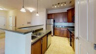 Located at 215 Reserve Blvd in Charlottesville, Virginia, this two-floor residence offers a thoughtfully designed layout with functional spaces throughout. The kitchen is a standout feature, showcasing rich cherry wood cabinetry, dark granite countertops, stainless steel appliances, and tile flooring. Track lighting and pendant fixtures illuminate a breakfast bar peninsula, creating a seamless connection to the carpeted living area, which is equipped with a ceiling fan.

Bedrooms are carpeted and filled with natural light from multiple windows, with tray ceiling detailing adding architectural interest. The primary bedroom benefits from a generously sized walk-in closet outfitted with wire shelving and hanging rods along multiple walls. Two bathrooms mirror each other in style, featuring cherry wood vanities with white countertops, tile flooring, and one includes a full tub-shower combination.

A dedicated laundry room houses a full-size washer and dryer alongside the water heater and electrical panel, adding practical utility. The attached garage offers a spacious, clean concrete-floored space with an automatic door opener. Warm, neutral tones carry throughout the residence, contributing to a cohesive and inviting overall ambiance.