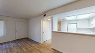 This single-floor residential unit offers a clean, functional layout with consistent wood-look flooring running throughout every room, creating a cohesive and easy-to-maintain living environment. The living area is open and well-proportioned, featuring a large window fitted with vertical blinds that allows natural light to fill the space, alongside a front entry door that provides direct access. An angled ceiling detail adds subtle architectural interest to this area.

The kitchen is efficiently designed in an L-shaped configuration and is equipped with white cabinetry offering ample upper and lower storage, white appliances including a refrigerator, electric range, microwave, and dishwasher, as well as a stainless steel sink. A skylight above the kitchen brightens the space naturally. A pass-through counter connects the kitchen to the living area, enhancing the open feel of the unit.

The unit includes two bedrooms, each finished with the same wood-look flooring and crisp white walls. One bedroom features a sliding-door closet with a full-width hanging rod, while the other includes a standard closet and a small window for ventilation and light. The full bathroom is neatly appointed with a tub-shower combination, toilet, and a vanity with a white countertop, all set against light, clean finishes throughout.
