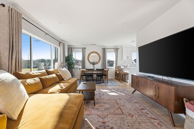 Living room with West Elm furniture, natural sunlight, and large TV flatscreen. - 1823 N Ditman Ave