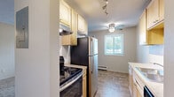 Located at 7501 Greenfield Ave in Mounds View, Minnesota, this two-bedroom unit offers a well-organized single-floor layout designed for comfortable everyday living. The galley-style kitchen features light wood cabinetry, stainless steel appliances including a full-size refrigerator and dishwasher, and durable tile flooring. Track lighting illuminates the workspace, and the layout flows efficiently toward the rest of the unit. The open living area is carpeted and benefits from a large window that invites natural light and outdoor views, complemented by a ceiling fan overhead and a baseboard heating system along the wall. Both bedrooms are carpeted and equipped with ceiling fans for year-round comfort. The spacious primary bedroom features two windows on separate walls, providing ample natural light and good ventilation. The second bedroom includes a full-width sliding closet, offering generous built-in storage. Textured ceilings are consistent throughout the unit, adding a classic residential character. Neutral wall tones and warm carpet tones create a cohesive, understated aesthetic throughout. The unit's efficient floor plan makes thoughtful use of its overall footprint, making it a practical and comfortable residence in the Mounds View community.