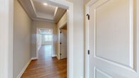 This well-appointed single-floor home combines classic architectural details with contemporary finishes to create a refined and cohesive living environment. The hallways set an elegant tone immediately, showcasing tray ceilings with recessed lighting, warm hardwood-style flooring, crisp white millwork, and paneled doors with distinctive matte black hardware that appear throughout the space.

The kitchen is a standout feature, outfitted with light wood-grain cabinetry, bright white quartz countertops, a herringbone tile backsplash, and a full suite of stainless steel appliances including a gas range. The layout provides generous counter space and ample storage, making it both functional and visually appealing.

A spacious walk-in closet offers a custom organizational system with dedicated shelving, hanging rails, and built-in drawers finished in a neutral wood tone, providing practical and stylish storage solutions.

The bathroom features a clean, minimalist design with wood-grain vanity cabinetry, white countertops, light tile flooring, and a tub-shower combination, all accented with matte black fixtures.

A carpeted bedroom with a tray ceiling, crown molding, a geometric pendant light, and a bright window offering natural light provides a calm, comfortable retreat. The attached garage is spacious and equipped with an automatic opener, completing this well-rounded home.