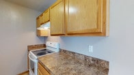 Located at 89 Riverview Dr in Saint Albans, West Virginia, this single-floor residence offers a practical and comfortable living environment. The kitchen is a standout feature of the home, showcasing warm honey-toned wood cabinetry that extends to the upper walls, providing generous storage space. The countertops display a laminate surface with a rich, earthy granite-like pattern, offering ample workspace for meal preparation. A white electric range is seamlessly integrated into the kitchen layout, positioned beneath a built-in range hood for effective ventilation. The cabinetry's natural wood finish lends a warm, welcoming atmosphere to the kitchen, complemented by soft, neutral-toned walls that keep the space feeling bright and open. The overall design reflects a straightforward, functional aesthetic suited for everyday living. Situated in Saint Albans, a community along the Kanawha River in West Virginia, this property combines practical interior features with the charm of its riverside location, making it a well-rounded option for those seeking comfortable, single-level living in the area.