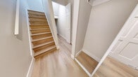 Located at 1923 Purcell Way in North Vancouver, BC, this well-appointed 2-bedroom, 1-bathroom unit offers a thoughtfully designed layout with a clean, modern aesthetic throughout. Light-toned engineered wood flooring flows continuously across the entire space, complementing the neutral, warm-white walls and creating a bright, cohesive atmosphere.

The open-concept kitchen and living area forms the heart of the unit, featuring stainless steel appliances, two-tone cabinetry with light wood lower cabinets and white uppers, recessed lighting, and generous floor space ideal for everyday living and entertaining. Large sliding glass doors open directly onto a private balcony, where lush, mature evergreen trees provide a serene natural backdrop.

Both bedrooms are comfortably sized, each offering closet storage — one with a mirrored sliding-door closet and another with a built-in rod closet. The bedrooms receive natural light through well-positioned windows overlooking the surrounding greenery. The bathroom is finished with warm wood-toned cabinetry, a white countertop, and consistent flooring throughout.

Additional features include a dedicated laundry area, multiple closets for ample storage, and staircase access. The overall design is clean, functional, and move-in ready.
