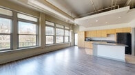 Located at 2010 Euclid Ave in Cleveland, OH, this 2-bedroom, 2-bathroom residence offers a thoughtfully designed single-floor layout with a distinctive industrial-loft aesthetic. The open-concept living, dining, and kitchen area serves as the heart of the home, featuring gleaming hardwood-style floors, exposed ductwork, and soaring ceilings that lend an airy, expansive feel. A wall of large windows floods the space with natural light while offering views of the surrounding cityscape and greenery. The kitchen is equipped with light maple cabinetry, granite-style countertops, a center island, tile flooring, and full appliances including a refrigerator and dishwasher. A dedicated laundry room with a stacked washer and dryer adds everyday convenience. The spacious primary bedroom features plush carpeting, generous closet space, and an en-suite bathroom. The second bedroom is similarly well-sized with its own closet. Both bathrooms are finished with tile flooring and clean, functional fixtures. A private balcony extends the living space outdoors. With four closets throughout, storage is plentiful. The unit's urban location and loft-inspired architecture make it a compelling option in the heart of Cleveland.