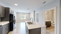 Located at 2430 W Kilgore Ave in Muncie, Indiana, this 2-bedroom, 1-bathroom unit offers a thoughtfully designed single-floor layout with modern finishes throughout. Light wood-style flooring flows consistently across all rooms, creating a clean, cohesive aesthetic complemented by neutral gray walls and white trim.

The kitchen is a standout feature, showcasing gray shaker-style cabinetry extending to the ceiling, light countertops, a kitchen island with a sink, and a full suite of black appliances including a range, microwave, and refrigerator. Recessed lighting brightens the space, which opens toward the living area for a connected feel.

The living area benefits from natural light through a window with outdoor views and is finished with recessed ceiling fixtures. Both bedrooms are well-proportioned, each equipped with a ceiling fan and light fixture. The primary bedroom offers a comfortable footprint, while the second bedroom features a set of double doors leading to a closet. A dedicated walk-in closet with built-in wire shelving provides ample organized storage.

The bathroom is finished with dark espresso vanity cabinetry, a white countertop, a large mirror, and a full tub-shower combination with clean white tile surround. The overall ambiance of this unit is fresh, modern, and move-in ready.