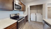 Located in Spokane Valley, WA, this single-floor unit at 701 N Conklin Rd offers a thoughtfully designed layout with functional living spaces throughout. The open-concept living area features neutral-toned carpet and recessed lighting, creating a bright and welcoming atmosphere. It flows seamlessly into the kitchen, which is equipped with rich dark wood cabinetry, light stone-look countertops, and a full suite of stainless steel appliances including a refrigerator, electric range, and over-the-range microwave. A peninsula counter provides additional workspace and a natural division between the kitchen and living area. Adjacent to the kitchen is a dedicated laundry area with a full-size washer and dryer. The bathroom features wood-look tile flooring, a dark wood vanity with a light countertop, a large mirror, and a tub-shower combination. The bedroom is carpeted and benefits from a window that allows natural light and exterior views of the surrounding community. A spacious walk-in closet with wire shelving provides generous storage. The unit's neutral color palette and consistent use of wood-look flooring in wet areas contribute to a cohesive and clean aesthetic throughout.