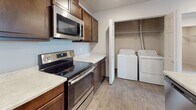 Located in Spokane Valley, WA, this single-floor unit at 701 N Conklin Rd offers a thoughtfully designed layout with functional living spaces throughout. The open-concept living area features neutral-toned carpet and recessed lighting, creating a bright and welcoming atmosphere. It flows seamlessly into the kitchen, which is equipped with rich dark wood cabinetry, light stone-look countertops, and a full suite of stainless steel appliances including a refrigerator, electric range, and over-the-range microwave. A peninsula counter provides additional workspace and a natural division between the kitchen and living area. Adjacent to the kitchen is a dedicated laundry area with a full-size washer and dryer. The bathroom features wood-look tile flooring, a dark wood vanity with a light countertop, a large mirror, and a tub-shower combination. The bedroom is carpeted and benefits from a window that allows natural light and exterior views of the surrounding community. A spacious walk-in closet with wire shelving provides generous storage. The unit's neutral color palette and consistent use of wood-look flooring in wet areas contribute to a cohesive and clean aesthetic throughout.