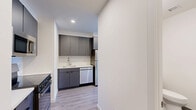 Located at 9 Homestead Place in Jersey City, NJ, this modern two-bedroom, one-bathroom residence offers a thoughtfully designed layout with contemporary finishes throughout. Light-toned hardwood flooring flows seamlessly across the living areas, complementing the clean white walls and creating a bright, cohesive aesthetic.

The galley-style kitchen is well-appointed with sleek charcoal cabinetry, a white tile backsplash, and a full suite of stainless steel appliances including a refrigerator, gas range, built-in microwave, and dishwasher — making it both functional and stylish.

Both bedrooms feature light wood-look flooring and stylish black-hardware barn-style sliding doors that open to closet spaces, adding a modern industrial touch. The primary bedroom is a comfortable size and is highlighted by a large picture window offering expansive views of the Jersey City skyline and beyond.

The bathroom is finished with a floating gray vanity, white quartz countertop, and a mirrored medicine cabinet. A space-saving stacked washer/dryer unit is conveniently integrated into the layout, providing in-unit laundry. With four closets throughout, storage is plentiful. This residence delivers a clean, modern living experience in a well-connected Jersey City location.