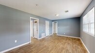 This compact and efficiently designed one-bedroom, one-bathroom residence offers a cohesive, single-floor layout that maximizes every square foot. A consistent warm-toned wood-look flooring and a cool blue-gray wall palette unify the entire space, creating a calm and modern aesthetic throughout.

The living room provides an open, airy feel with clean white trim and good ceiling clearance, connecting seamlessly to the rest of the unit via a central hallway. The kitchen is a standout feature, equipped with crisp white shaker-style cabinetry, granite-look countertops, a white subway tile backsplash, and a full suite of black appliances including a gas range, dishwasher, and refrigerator — offering both style and practicality.

The bedroom is a comfortable and well-proportioned retreat, featuring a window that allows natural light to filter in, a dedicated walk-in closet with hanging rod, and the same consistent flooring and wall tones found throughout the unit.

The bathroom is neatly appointed with a white tile tub-and-shower surround, a granite-topped vanity, and wood-look flooring that ties in with the rest of the space. A closet and hallway round out the layout, providing practical storage and smooth flow between rooms. The overall ambiance is clean, modern, and move-in ready.