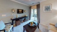 Located at 1150 Baxter Ln in Knightdale, NC, this well-appointed single-floor residence offers a thoughtfully designed layout with an inviting, cohesive aesthetic throughout. The kitchen is a functional centerpiece, featuring rich warm-toned cabinetry, granite-style countertops, black appliances, and a built-in desk area — all complemented by hardwood-style flooring and pendant lighting that adds a modern touch. A breakfast bar provides casual seating and opens toward the main living areas. The living room is bright and comfortable, highlighted by crown molding, soft carpet, and sliding glass doors that lead to a private patio with outdoor views. A separate dining area features a teal accent wall, crown molding, and a pendant light fixture, creating an intimate setting for meals. The bedrooms are generously sized with plush carpeting, ceiling fans, and walk-in closets. One bedroom includes a bold teal accent wall, while another features an en-suite bathroom with white cabinetry and a tub-shower combination. The bathrooms throughout are finished with tile flooring, white vanities, and tub-shower combos, maintaining a clean and classic look. Overall, the space balances warm, neutral tones with coordinated accent colors for a polished and livable environment.