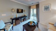 Located at 1150 Baxter Ln in Knightdale, NC, this well-appointed single-floor residence offers a thoughtfully designed layout with an inviting, cohesive aesthetic throughout. The kitchen is a functional centerpiece, featuring rich warm-toned cabinetry, granite-style countertops, black appliances, and a built-in desk area — all complemented by hardwood-style flooring and pendant lighting that adds a modern touch. A breakfast bar provides casual seating and opens toward the main living areas. The living room is bright and comfortable, highlighted by crown molding, soft carpet, and sliding glass doors that lead to a private patio with outdoor views. A separate dining area features a teal accent wall, crown molding, and a pendant light fixture, creating an intimate setting for meals. The bedrooms are generously sized with plush carpeting, ceiling fans, and walk-in closets. One bedroom includes a bold teal accent wall, while another features an en-suite bathroom with white cabinetry and a tub-shower combination. The bathrooms throughout are finished with tile flooring, white vanities, and tub-shower combos, maintaining a clean and classic look. Overall, the space balances warm, neutral tones with coordinated accent colors for a polished and livable environment.
