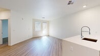 This well-appointed single-floor residence offers a clean, contemporary design throughout. The open-concept kitchen is a standout feature, equipped with stainless steel appliances including a refrigerator, gas range, and built-in microwave, complemented by warm wood-toned cabinetry, white quartz countertops, a subway tile backsplash, and a peninsula with an integrated sink and industrial-style faucet. Recessed lighting illuminates the kitchen space, which flows seamlessly into the main living area.

Light-toned hardwood-style flooring runs throughout the residence, enhancing the bright and airy atmosphere created by the crisp white walls and natural light streaming through multiple windows fitted with horizontal blinds. The spacious living and bedroom areas offer generous room for furnishings and personal arrangement.

A dedicated in-unit laundry closet houses a stacked washer and dryer, adding notable convenience. The walk-in closet provides abundant storage with built-in shelving units and hanging rods on multiple walls. The bathroom features a large walk-in shower enclosed by a frameless glass door, with elegant large-format tile surround in neutral tones and a clean white shower pan. The overall ambiance of the space is modern, light, and move-in ready.