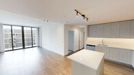 This well-appointed 2-bedroom, 2-bathroom residence offers a thoughtfully designed single-floor layout that balances modern aesthetics with functional living. The open-concept kitchen and living area serves as the heart of the home, featuring warm hardwood-style flooring, sleek light wood cabinetry extending to the ceiling, white quartz countertops, stainless steel appliances, a built-in wine cooler, and a central island perfect for dining or entertaining. The living room is flooded with natural light through expansive floor-to-ceiling sliding glass doors that open to a private balcony, offering stunning views of a resort-style courtyard complete with a pool, palm trees, and lush greenery. Both bedrooms are carpeted for comfort and include ceiling fans and dedicated closets. The primary bathroom is outfitted with a double-sink vanity topped with quartz counters, light wood cabinetry, and dual backlit mirrors, while the second bathroom features a similarly refined single-vanity design. Clean white walls, crisp trim, and consistent modern finishes throughout create a bright, cohesive ambiance that is both sophisticated and inviting.