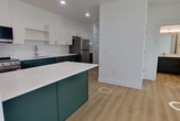This 790-square-foot single-floor residence in Washington, Utah features a clean, modern design with bright white walls, light wood-look flooring in the main living areas, and an open, airy feel throughout. The combined kitchen and living room serves as the heart of the home, with the kitchen showcasing two-tone cabinetry — deep forest green lower cabinets paired with white upper cabinets — complemented by white quartz countertops, a center island, recessed lighting, and a full suite of stainless steel appliances including a refrigerator, range, microwave, and dishwasher. The living room features large windows with blinds, allowing natural light to fill the space. Both bedrooms are carpeted and generously windowed, with the primary bedroom spanning 130 square feet. The two bathrooms mirror the kitchen's dark cabinetry style, each featuring white quartz vanity tops and light wood-look flooring. The primary bathroom includes a full tub-shower combo with built-in shelving, while the secondary bathroom offers a streamlined vanity with ample storage. A dedicated closet provides additional storage. The unit's consistent modern aesthetic and neutral palette create a cohesive, move-in-ready living environment.