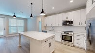 This well-appointed 2-bedroom, 2-bathroom single-story residence offers a thoughtfully designed layout across a comfortable footprint. The open-concept kitchen serves as the centerpiece of the home, showcasing crisp white shaker cabinetry with black hardware, a classic subway tile backsplash, quartz countertops, and a full suite of stainless steel appliances including a range, built-in microwave, dishwasher, and refrigerator. A large central island with pendant lighting provides additional prep space and connects seamlessly to the living area, which benefits from natural light streaming through multiple windows.

Both bedrooms feature neutral-toned carpet, ceiling fans, and generous windows with blinds that invite natural light while maintaining privacy. The primary bedroom includes its own dedicated walk-in closet with wire shelving for ample storage, while the second closet offers similar functionality.

Each bathroom is finished with distinctive blue vanity cabinetry, white quartz countertops, and light wood-look flooring. The primary bath includes a double-sink vanity, a glass-enclosed walk-in shower, and direct access to the walk-in closet. The second bathroom features a tub-shower combo with white subway tile surround. Light wood-look flooring flows throughout the main living areas, tying the entire home together with a clean, contemporary aesthetic.
