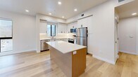 Located at 3130 S Highland Dr in Millcreek, Utah, this thoughtfully designed 2-bedroom, 2-bathroom residence offers a modern aesthetic throughout its well-appointed single-floor layout. Light wood flooring flows seamlessly across all living areas, complementing the clean, neutral palette that defines the space.

The open-concept kitchen, dining, and living area serves as the heart of the home. The kitchen is outfitted with crisp white shaker cabinetry, a white quartz countertop island with warm wood paneling, stainless steel appliances including a range, microwave, refrigerator, and dishwasher, and a classic subway tile backsplash with under-cabinet lighting.

The spacious primary bedroom is bathed in natural light through large black-framed windows that frame sweeping views of the surrounding mountains. The second bedroom also features generous windows with outdoor views. Both bathrooms are finished in a clean, contemporary style with tub-shower combinations, white tile surrounds, built-in open shelving, and brushed nickel fixtures.

A well-lit hallway connects the living areas to the private quarters, with two closets providing ample storage. Additional conveniences include a dedicated laundry area, utility room, and a private balcony. Recessed lighting throughout adds a refined, modern touch.